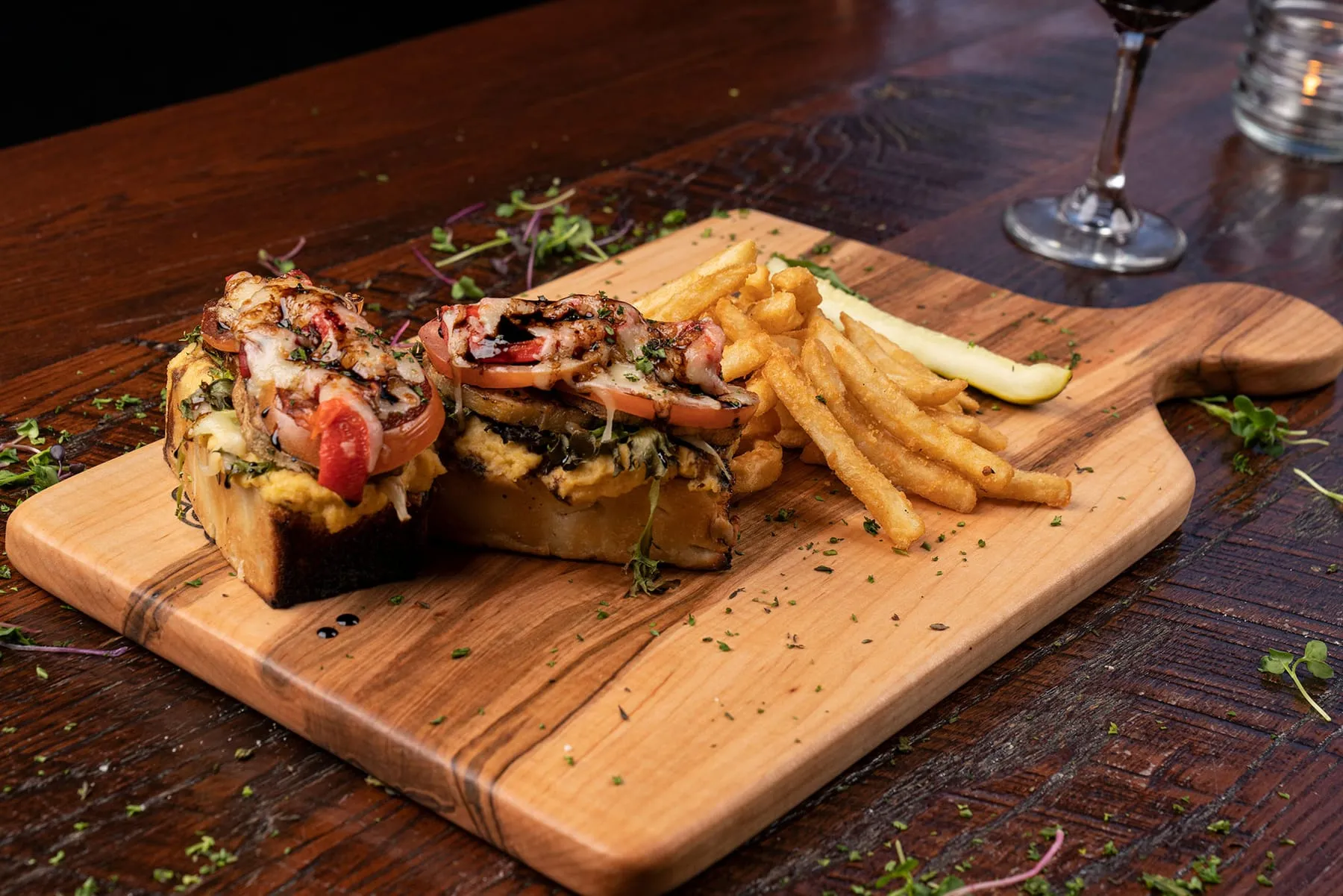 Veggie ciabatta on a board with fries and a pickle
